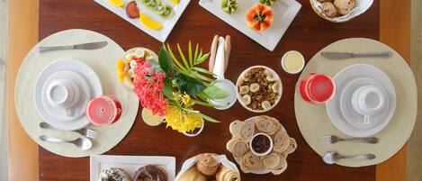 A breakfast buffet with various food items and utensils laid out on a wooden table.