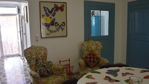 A room with two floral armchairs, a round table with a butterfly-themed tablecloth, and a framed butterfly artwork on the wall. - Oberdan Suites with Terrace (historical apartment in Alberobello) (Alberobello)