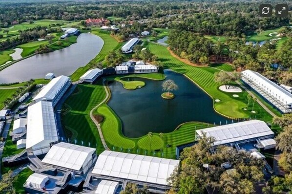Vista aérea de un campo de golf con varias edificaciones, un lago y zonas verdes cuidadas.
