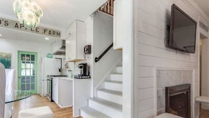 A modern kitchen with white cabinets, a green door, and a staircase leading to a living area with a fireplace. - Heart Of The City ❤️ Hot tub, ITB, NC State Cameron Village  (Raleigh)