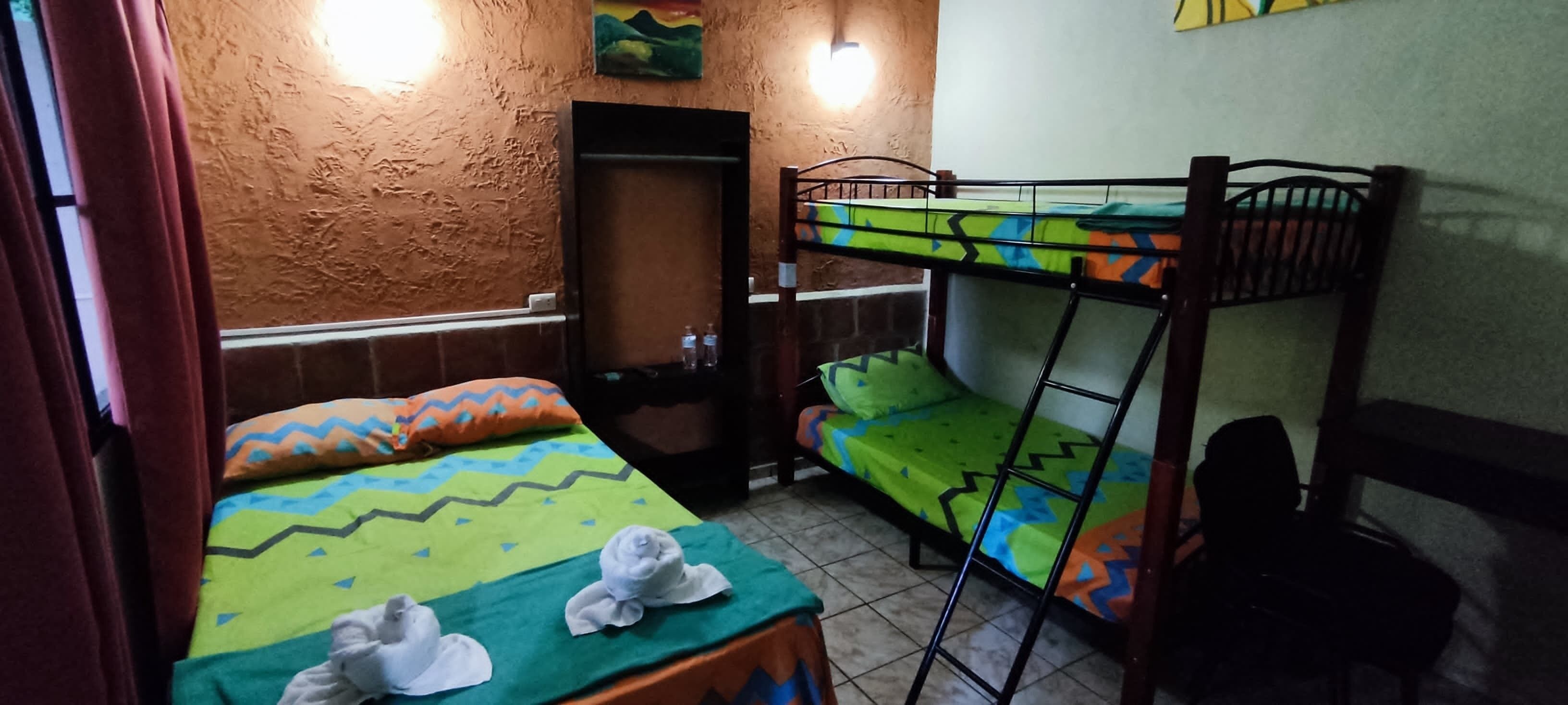 A dormitory room with bunk beds, a wardrobe, and a mirror.
