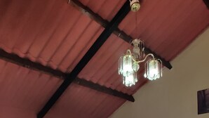 Una habitació amb dos llits, una banca de fusta, un ventilador de sostre i un penjador.