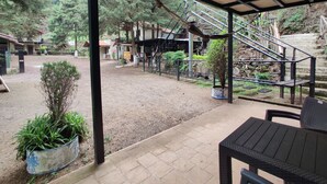 A covered outdoor area with a dirt ground, a metal staircase, and a potted plant. - Bosques del Tibet (Santa Ana)