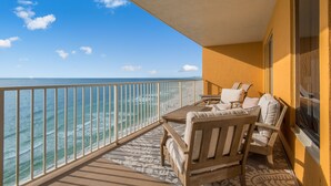 A balcony with a view of the ocean, wooden furniture, and a patterned rug. - Treasure Island 0805 (Panama City Beach)