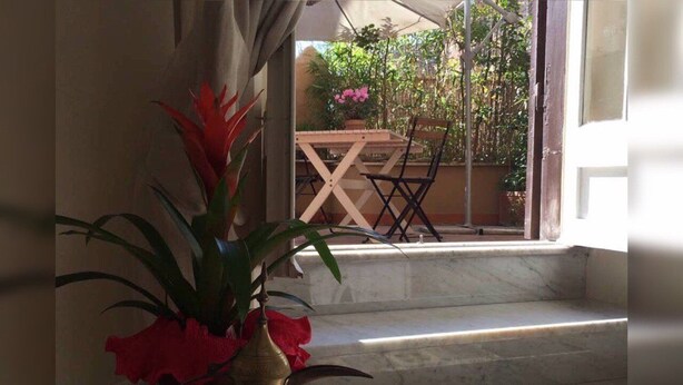 Un escalier en marbre mène à un espace extérieur où se trouvent une table et des chaises en bois.