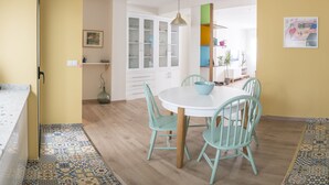 Un comedor con una mesa redonda, cuatro sillas y un armario con puertas de vidrio.