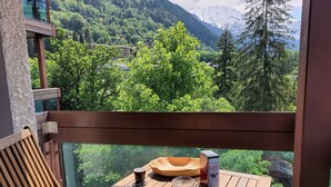 A balcony with a wooden table, a chair, a box of coffee, and a cup. - Beautiful apartment for 4 guests with WIFI, TV and balcony (Saint-gervais-les-bains)