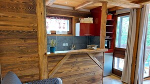 A cozy cabin interior with a wooden interior, a kitchenette, and a living area with a couch and a table. - Beautiful apartment for 4 guests with WIFI, TV and balcony (Saint-gervais-les-bains)