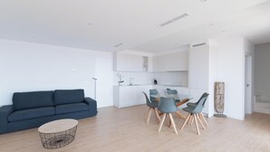 A modern living room with a blue sofa, a round coffee table, and a dining area with a glass table and four chairs. - Premium villa with private pool and sea views (Ancla Mar nº4) (Roses)