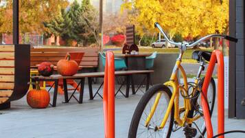 A bicycle parked at a bike rack, a wooden bench, and a pumpkin decoration on the ground.