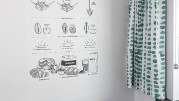 Une pièce avec un fauteuil orange au design moderne, une table en bois et un mur orné d’illustrations sur le thème de l’agriculture.