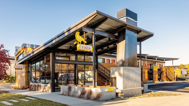 Un edificio moderno con una gran escultura de un pájaro amarillo, una escalera y un letrero que dice "FINCH".
