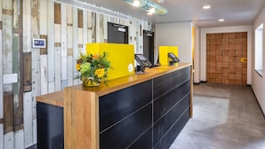 Una recepción con encimera de madera y base negra, un separador amarillo y un arreglo floral.