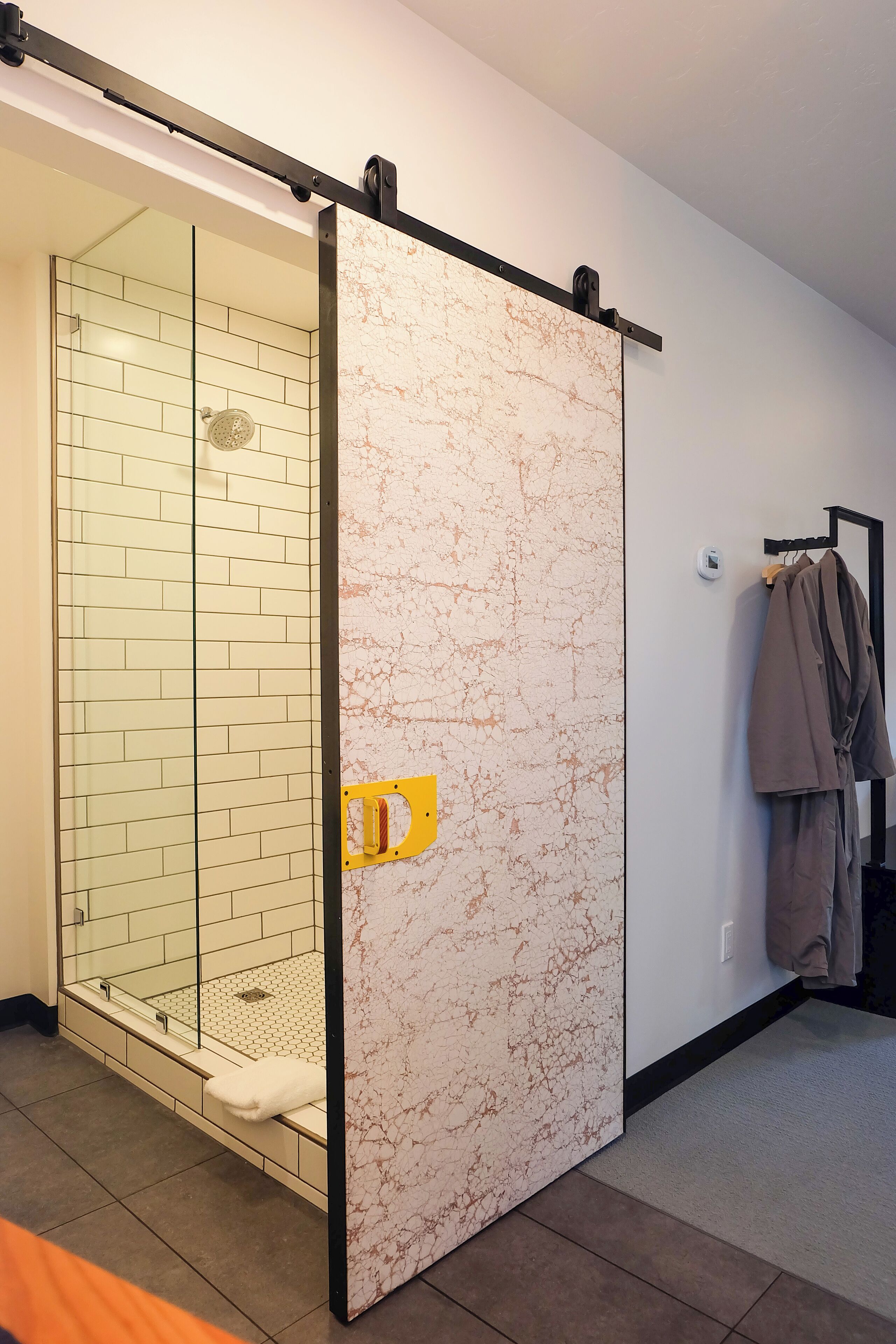 Ein Badezimmer mit Glasdusche, Marmorwaschtisch und einem Handtuchhalter mit Bademantel.