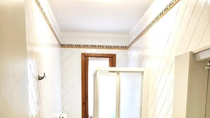 A bathroom with two toilets, a sink, a shower enclosure, and a radiator.