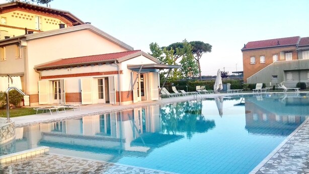 A swimming pool with lounge chairs and a building with a tiled roof.