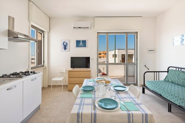 A compact living space with a kitchenette, dining area, and a bed.