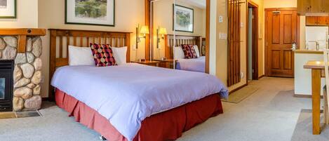 A bedroom with a large bed, a stone fireplace, and a wooden wardrobe.