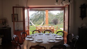 A dining room with a table set for six, overlooking a garden with a hammock and a brick structure. - Villa with view of the Poppi castle, unlimited Internet use (Poppi)
