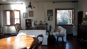 A spacious living room with a wooden dining table, two sofas, a fireplace, and large windows. - Villa with view of the Poppi castle, unlimited Internet use (Poppi)
