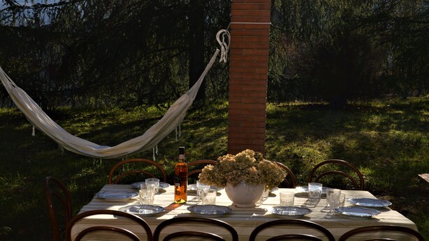 An outdoor dining table set up with chairs, a hammock, and a brick pillar. - Villa with view of the Poppi castle, unlimited Internet use (Poppi)