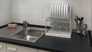 A modern kitchen with white cabinets, a black countertop, and a dish drying rack.