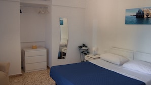 A bedroom with a bed, a bedside table, a mirror, a dresser, and a wall-mounted picture.