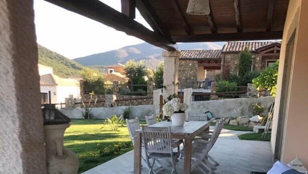 Eine Außenpatio mit Holztisch und Stühlen, einer Korbusitzgruppe und einer dekorativen Laterne.