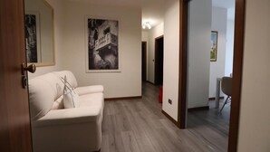A hallway with a white sofa, a framed black and white photo, and a wooden door.