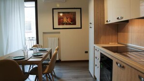 A modern kitchen with wooden cabinets, a built-in oven, and a dining area with a table set for two.