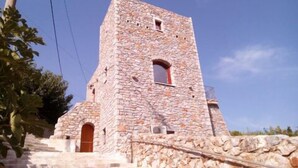Uma torre de pedra com uma pequena janela e uma porta na base.