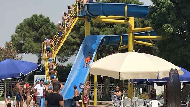 A water park with a large blue slide, a pool area with lounge chairs, and umbrellas providing shade. - Residence Lamezia Golfo (Lamezia Golfo)