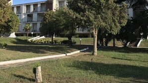 A residential building with a flat roof, multiple balconies, and a well-maintained lawn with trees. - Residence Lamezia Golfo (Lamezia Golfo)