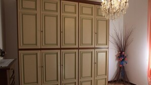 Un dormitorio con un armario grande, una cama con ropa de cama floral y una araña.
