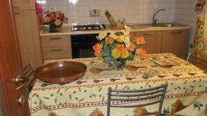 Una cocina con armarios de madera, un lavamanos, una estufa y una mesa de comedor con mantel floreado.