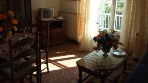 Una habitación con una mesa de comedor, sillas, televisión y una ventana con cortinas.