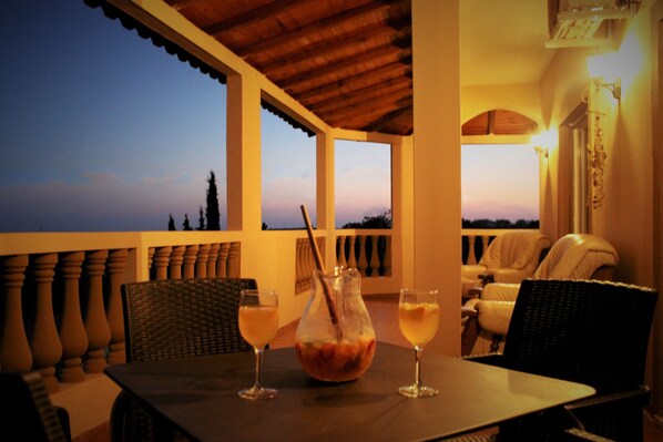 A dining table with two glasses of a light-colored beverage, a pitcher, and wicker chairs. - Villa Rios Garden - Perfect for Resting, Relaxing and Enjoying Nature (Franqueira)