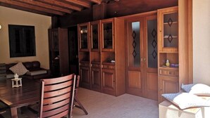 Una habitación acogedora con muebles de madera, que incluyen una mesa de comedor y sillas, y armarios empotrados de madera con puertas de cristal.