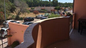 Un balcón con vistas a un estacionamiento y zonas verdes.