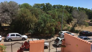 Un estacionamiento cerrado con varios coches, cielo despejado y follaje circundante.