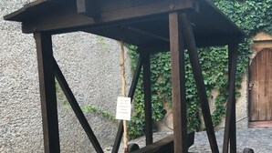 En träkonstruktion med en sluttande bänk och hjul, eventuellt en historisk utställningsdel eller ett monument.