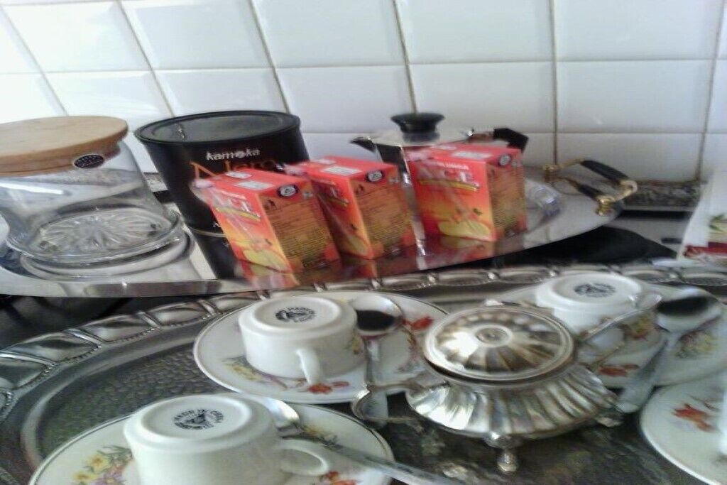 Un piano di lavoro in cucina con un fornello a gas, una macchina da caffè e diverse teiere e tazze.