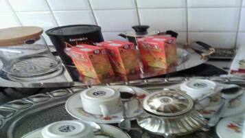 Un piano di lavoro in cucina con un fornello a gas, una macchina da caffè e diverse teiere e tazze.