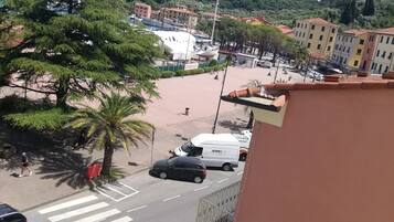 Vista de la calle con un paso de peatones, coches estacionados y edificios al fondo.