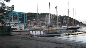 A marina with boats docked, a small jetty, and a row of white lounge chairs. - Freedom apartment (Portovenere)