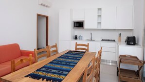 A compact kitchen with white cabinets, a microwave, a gas stove, and a coffee maker. - RANDOM LISTING (San Vito Lo Capo)