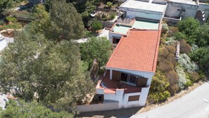 Un edificio de dos pisos con techo de tejas rojas, rodeado de árboles y vegetación.