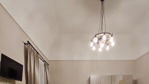 Un dormitorio con cama, mesita de noche, cuna, armario, espejo, televisor y candelabro.