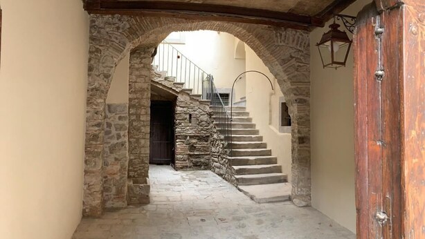Un arco de piedra que da paso a una escalera con una puerta de madera a la derecha.