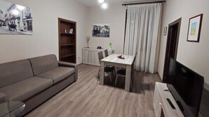 Una sala de estar moderna con un sofá, una mesa de comedor, un televisor y una estantería.
